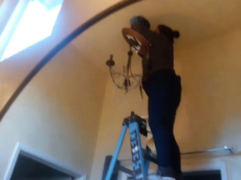 Electrician installing a chandelier in a Central residence